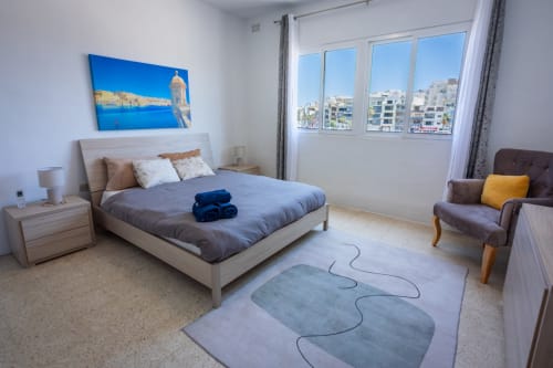 Luminosa camera da letto con vista mare a Marsaskala, letto queen size, poltrona e arredamento moderno con affaccio sul mare