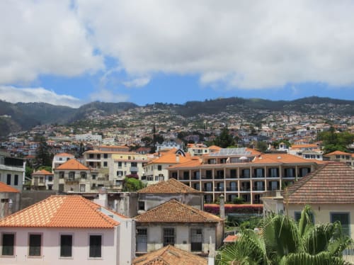 Casarões coloridos em Funchal, Portugal com telhados de barro e montanhas ao fundo