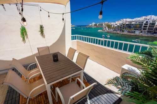 Terrazza fronte mare con tavolo da pranzo, ombrellone e vista sul mare turchese della casa a Marsaskala, Malta