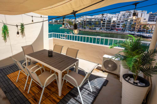 Terrazza sul tetto con vista sul mare a Marsaskala con tavolo da pranzo, sedie, ombrellone e vista sui palazzi del waterfront