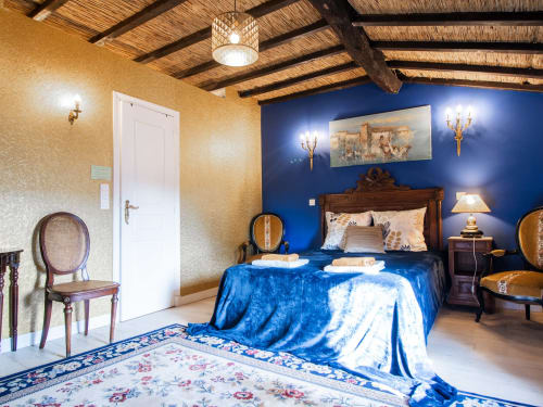 Chambre Deluxe Bleue à L'Ecrin des Roches B&B au Langon, France, avec murs bleu élégant, poutres en bois et décor raffiné
