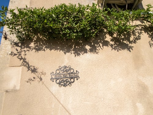 Mur ensoleillé de la cour intérieure à L'Ecrin des Roches avec lierre grimpant et plaque métallique ornementale, Le Langon