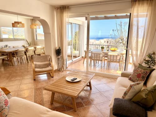 Luminosa zona de estar abierta en Villa Sienna, Nerja con vistas al mar, muebles de madera y acceso a terraza