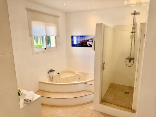 Baño moderno en Villa Sienna, Nerja con bañera de hidromasaje en esquina, ducha walk-in y TV de pantalla plana