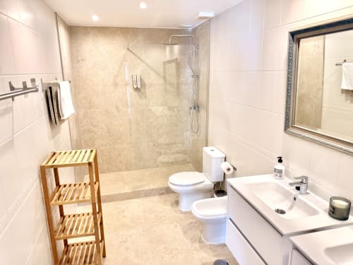 Baño moderno en Villa Sienna, Nerja con ducha de mármol, doble lavabo, estante de madera y azulejos blancos