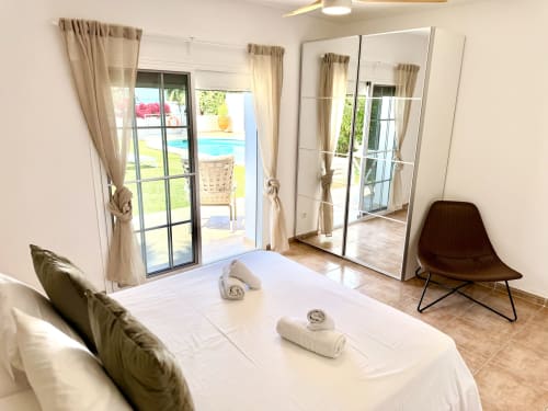 Dormitorio luminoso en Villa Sienna, Nerja con vistas al mar, armario espejo, cama con toallas y acceso a piscina