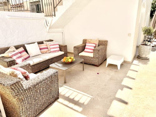 Terraza soleada con muebles de mimbre, cojines a rayas y frutero en Villa Sienna, Nerja