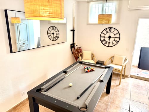 Sala de recreo en Villa Sienna, Nerja con billar, relojes decorativos, sillas de madera y lámparas colgantes tejidas