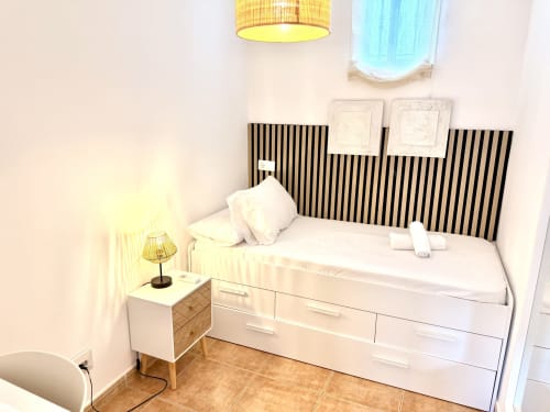 Dormitorio moderno en Villa Sienna, Nerja con cama blanca, cabecero a rayas negras y lámpara