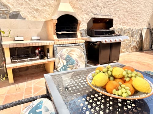 Cocina y comedor exterior de Villa Sienna en Nerja con parrilla, tabla de frutas frescas y patio de terracota