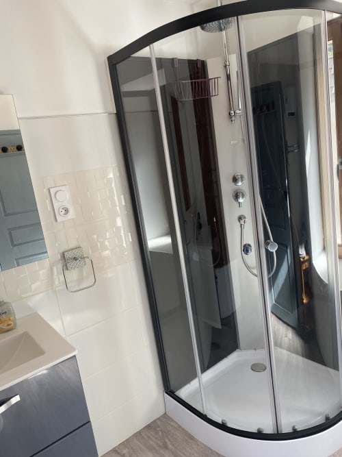 Douche d'angle moderne aux montants noirs dans la salle de bains de l'appartement L'encabanée, Saint-Paul-sur-Ubaye