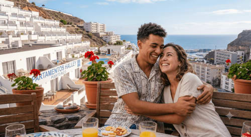 Happy couple enjoying breakfast with ocean views at Halley Apartments in Puerto de Mogán, Spain