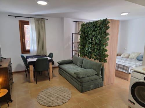 Apartamento abierto en Apartamentos el Manantial de Chóvar con sofá verde, comedor y dormitorio visibles