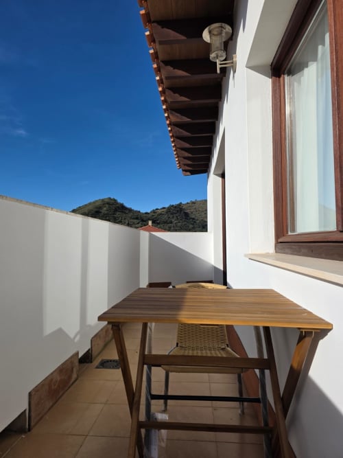 Terraza soleada de Apartamentos el Manantial de Chóvar con mesa de madera, vistas a las montañas y paredes blancas