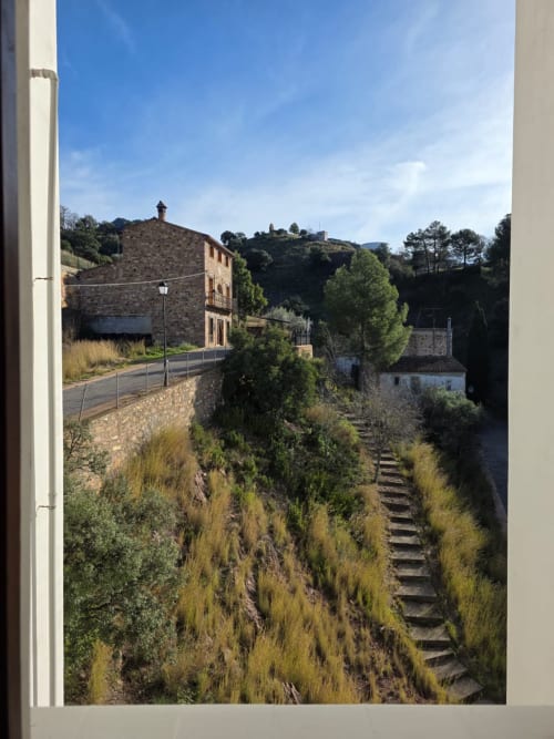 Pueblo toscano rústico con edificios de piedra, escaleras en la ladera y vistas al campo desde Apartamentos el Manantial de Chóvar