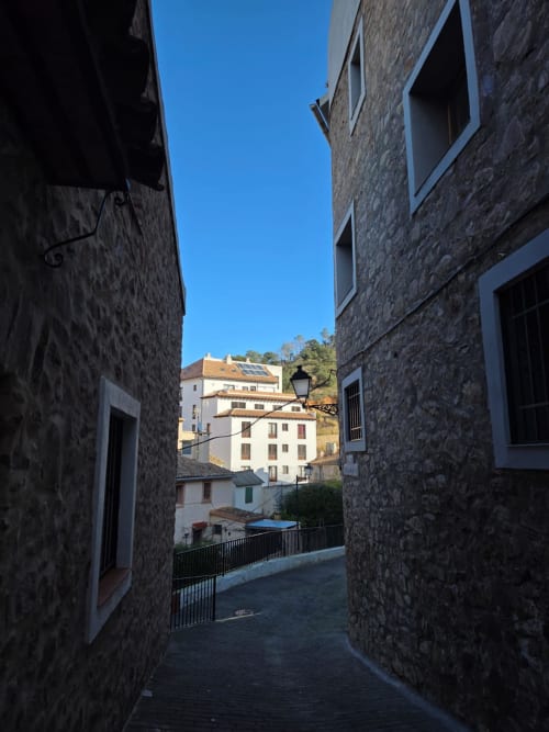 Estrecho callejón de piedra en el pueblo de Chóvar con edificios históricos y vistas a la montaña, Apartamentos el Manantial