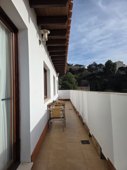 Terraza estrecha en Apartamentos el Manantial de Chóvar con vistas montañosas, paredes blancas, vigas de madera y zona de estar exterior