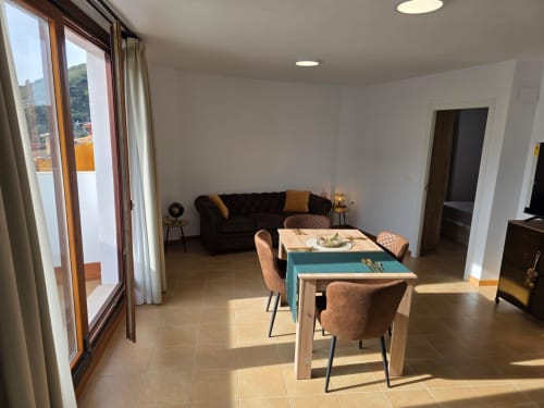 Espaciosa sala de estar diáfana en apartamento El Manantial de Chóvar con comedor, sofá, vistas a la montaña y acceso a balcón