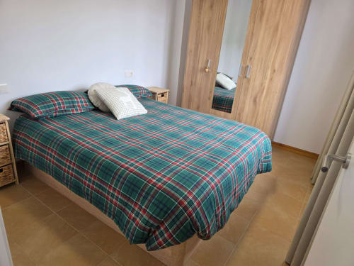 Habitación en Apartamentos el Manantial de Chóvar con ropa de cama a cuadros, armarios de madera y suelo de baldosas
