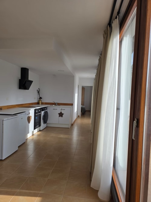Cocina moderna con gabinetes blancos, piso de cerámica marrón y amplias ventanas con vistas a las montañas en Apartamentos el Manantial