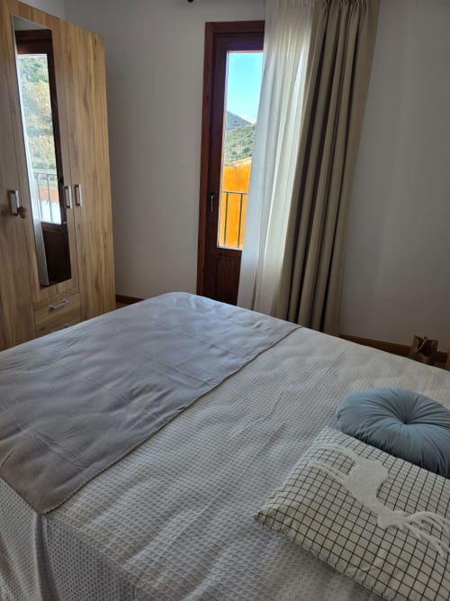 Dormitorio moderno en Apartamentos el Manantial de Chóvar con vistas a las montañas, cama doble, armario de madera y acceso a balcón