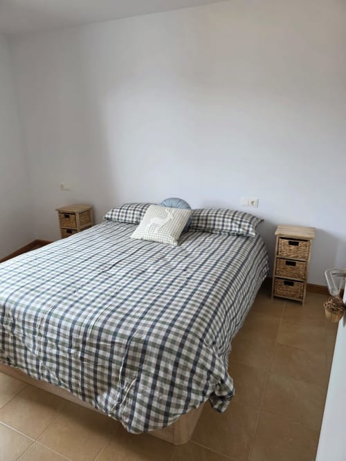 Dormitorio en Apartamentos el Manantial de Chóvar con ropa de cama de cuadros azules, mesillas de madera y vistas a las montañas
