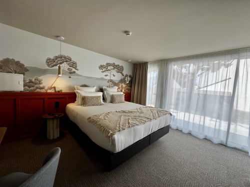 Chambre royale moderne à l'Hôtel des Quatre Saisons à Guérande avec tête de lit rouge, accès à la terrasse et peinture murale nature