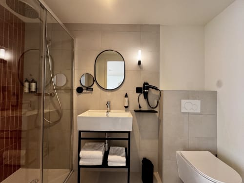 Salle de bains moderne de l'Hôtel des Quatre Saisons avec douche à l'italienne, double vasque et équipements contemporains