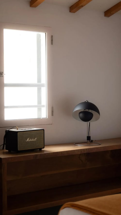 Minimalist hotel room at Hotel Fragile in Menorca with desk lamp, Marshall speaker, and bright window view