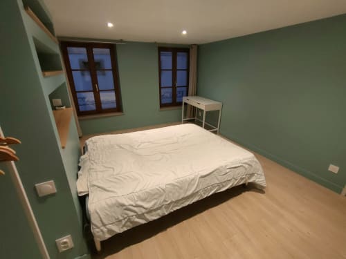 Chambre moderne de l'appartement Mattbnb à Metz avec murs verts, lit, bureau et vue sur la ville depuis les fenêtres