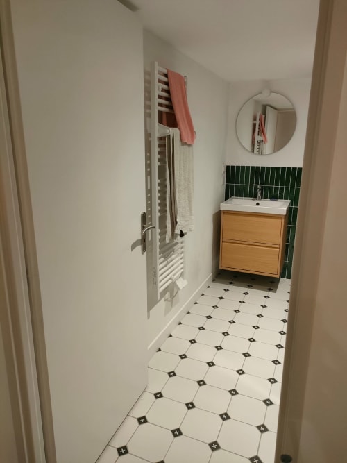 Salle de bain moderne de l'appartement Mattbnb à Metz : carrelage noir et blanc, meuble-lavabo en bois, dosseret en carrelage vert, miroir