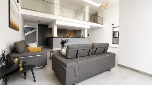 Modern studio apartment living room in Dakar with gray sofa, kitchenette, and contemporary furnishings