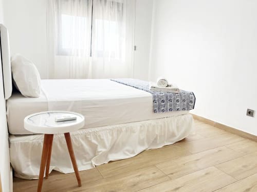 Bright bedroom in DakarByDays apartment with white bed, wooden nightstand, and light wood flooring in Dakar