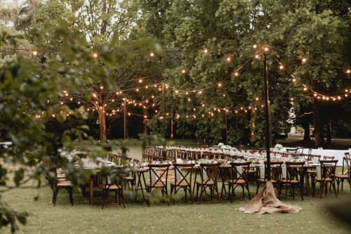 Ricevimento di matrimonio all'aperto a Palazzo Bonfiglioli con luci decorative, sedie in legno e lussureggiante verde a San Giovanni in