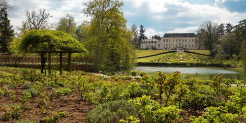 Le château de luxe La Grange Aux Etangs avec ses jardins soignés, étang et feuillage printanier à Sennely, France