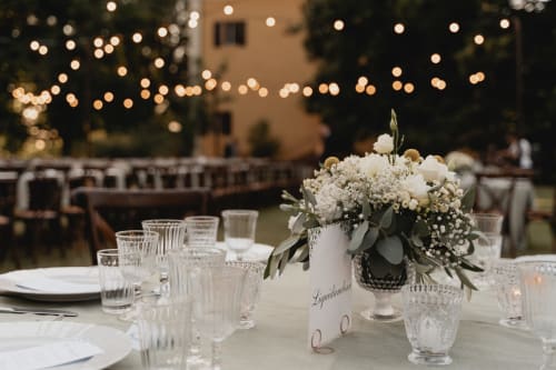 Tavolo elegante per matrimonio all'aperto a Palazzo Bonfiglioli con fiori bianchi, luci soffuse e cristalleria scintillante