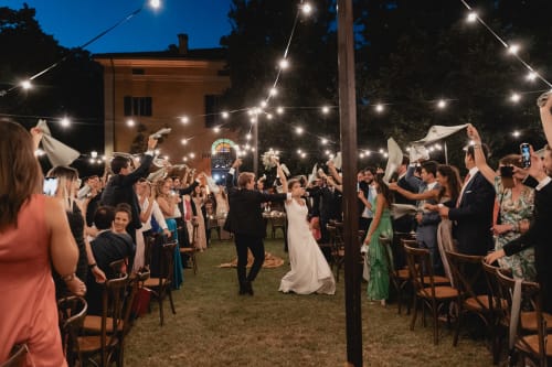 Celebrazione di nozze serale a Palazzo Bonfiglioli con ospiti che sventolano tovaglioli sotto le luci decorative a San Giovanni in