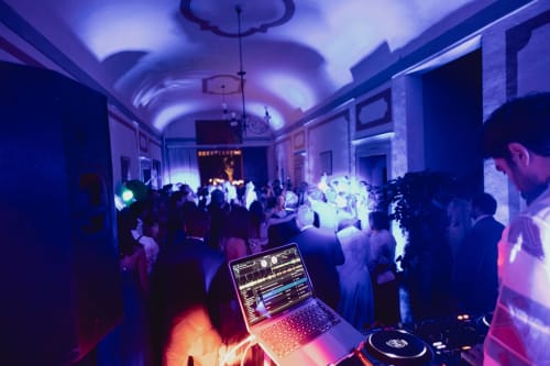 Cabina DJ con laptop in una elegante sala del Palazzo Bonfiglioli illuminata da luci viola vibranti, San Giovanni in Persiceto