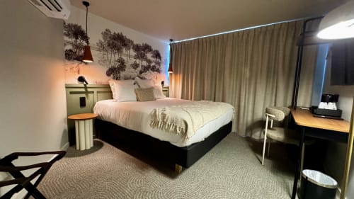 Chambre moderne de l'Hôtel des Quatre Saisons à Guérande avec lit queen, luminaires suspendus, œuvres d'art murales et espace de travail