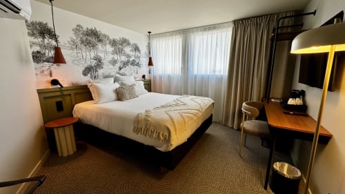 Chambre moderne de l'Hôtel des Quatre Saisons à Guérande avec lit queen-size, bureau, télévision et éclairage chaleureux
