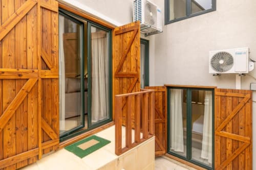 Pátio do apartamento de jardim no rés do chão da AgapeStay Porto com venezianas de madeira, portas de vidro e unidades de AC no Porto, Portugal
