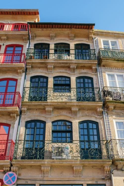 Fachada histórica do Porto com varandas ornamentadas, colunas de pedra e janelas em arco na AgapeStay