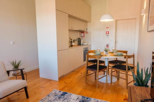 Cozinha e sala de jantar integradas modernas no apartamento duplex AgapeStay Porto, com mesa de madeira, armários bege e piso em madeira