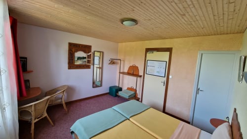 Chambre avec deux lits et vue sur la rivière à l'Hôtel Rose à Beauvoir, avec plafond en bois et décor vintage