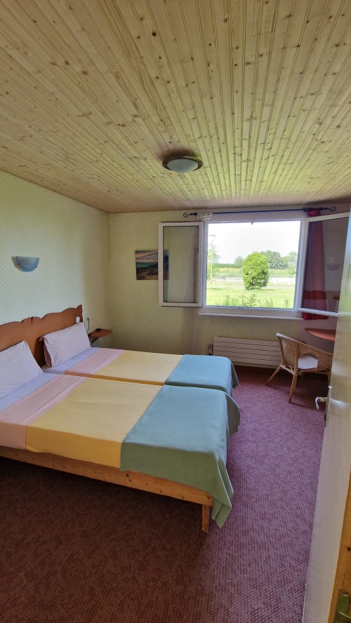 Chambre twin avec vue sur la rivière à l'Hôtel Rose, Beauvoir, plafond à poutres apparentes et paysage champêtre