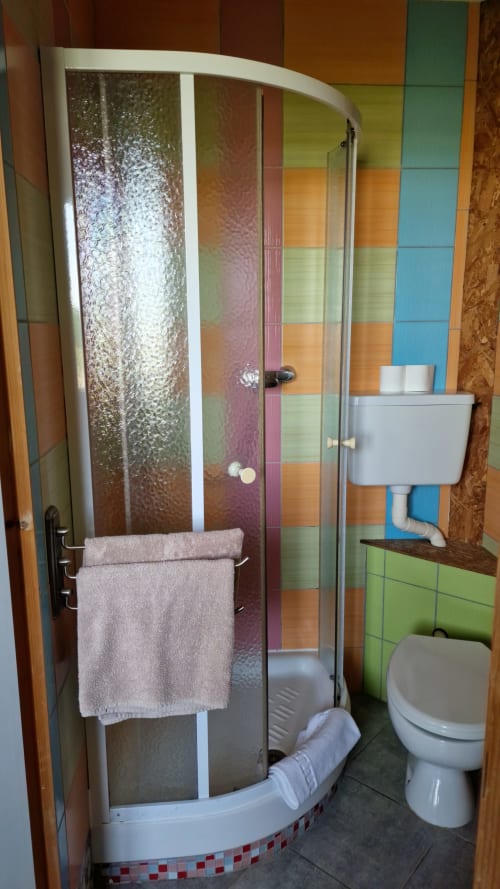 Salle de bain colorée avec douche d'angle et lavabo blanc à l'Hôtel Rose, Beauvoir