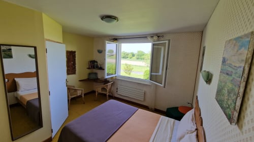 Chambre double lumineuse avec vue sur la rivière à l'Hôtel Rose à Beauvoir, France, dotée d'un lit, d'un bureau et de fenêtres