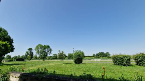 Vaste pelouse verdoyante à l'Hôtel Rose à Beauvoir avec arbres dispersés et vues sur la rivière