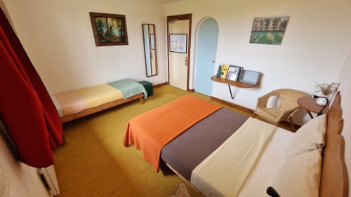 Chambre triple avec vue sur la rivière à l'Hôtel Rose à Beauvoir, avec lits et coin salon