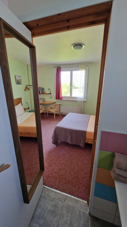 Chambre triple avec vue sur la rivière à l'Hôtel Rose, Beauvoir, lit, bureau, murs verts et fenêtre donnant sur la rivière